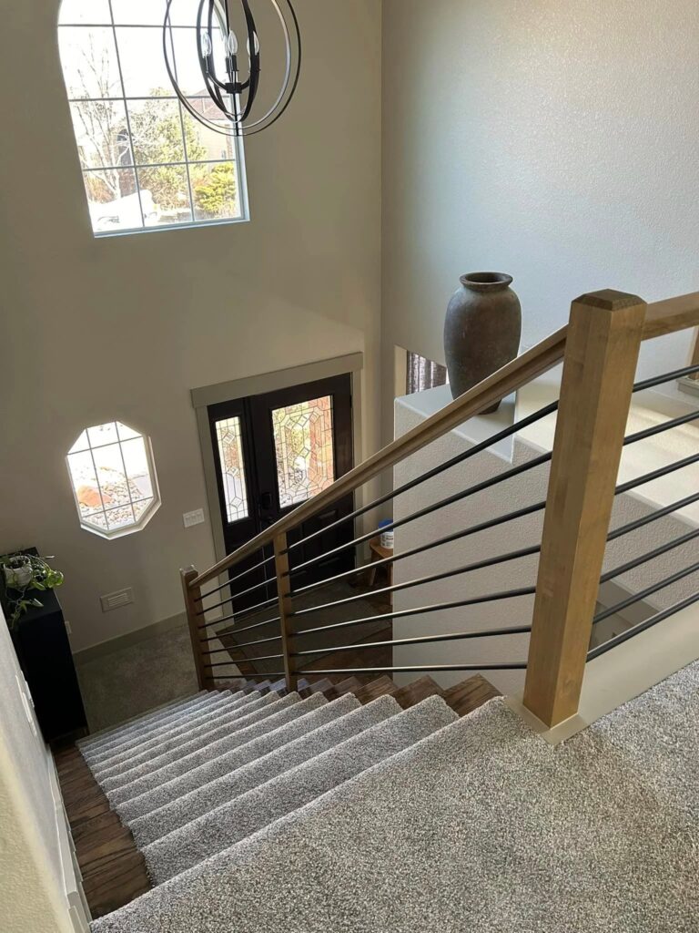 Entry and stair with horizontal steel rail and octagonal window after the Windsor remodel